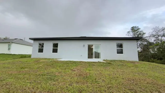 a house that is sitting in the grass with large trees