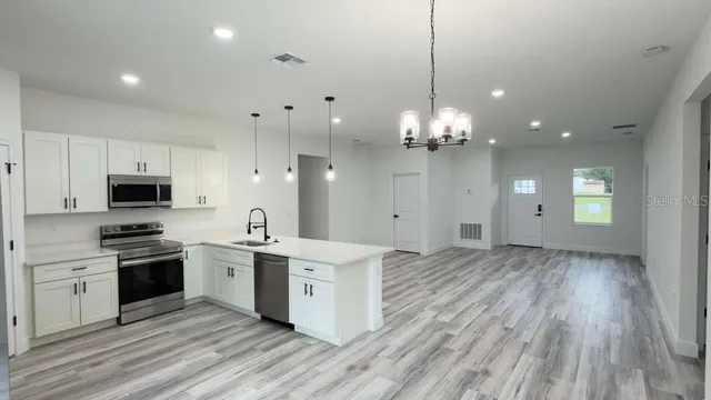 a large kitchen with granite countertop a stove top oven a sink dishwasher and a refrigerator with wooden floor