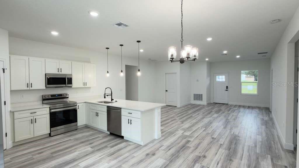 14905 Southwest 24th Circle Ocala, FL 34472 - Photo 5 of 24 a large kitchen with granite countertop a stove top oven a sink dishwasher and a refrigerator with wooden floor