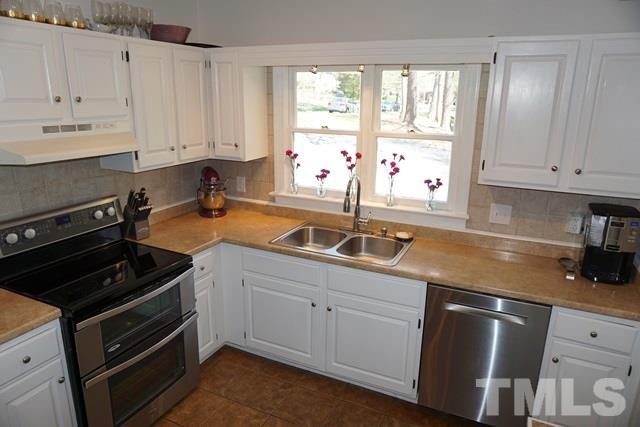 215 Danforth Drive Cary, NC 27511 - Photo 7 of 25 a kitchen with granite countertop white cabinets and white appliances