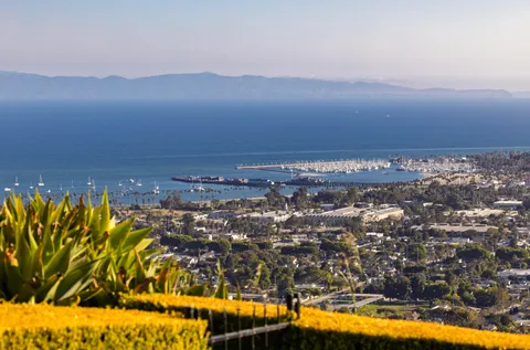 a front view of residential houses with yard and mountain view in back