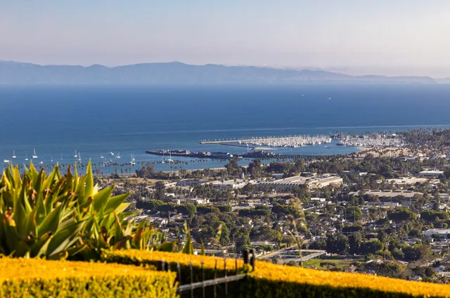 a front view of residential houses with yard and mountain view in back