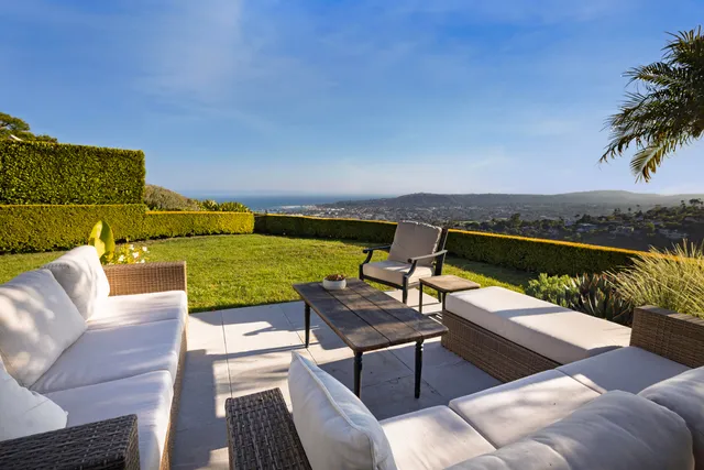 a view of a patio with couches table and chairs under an umbrella