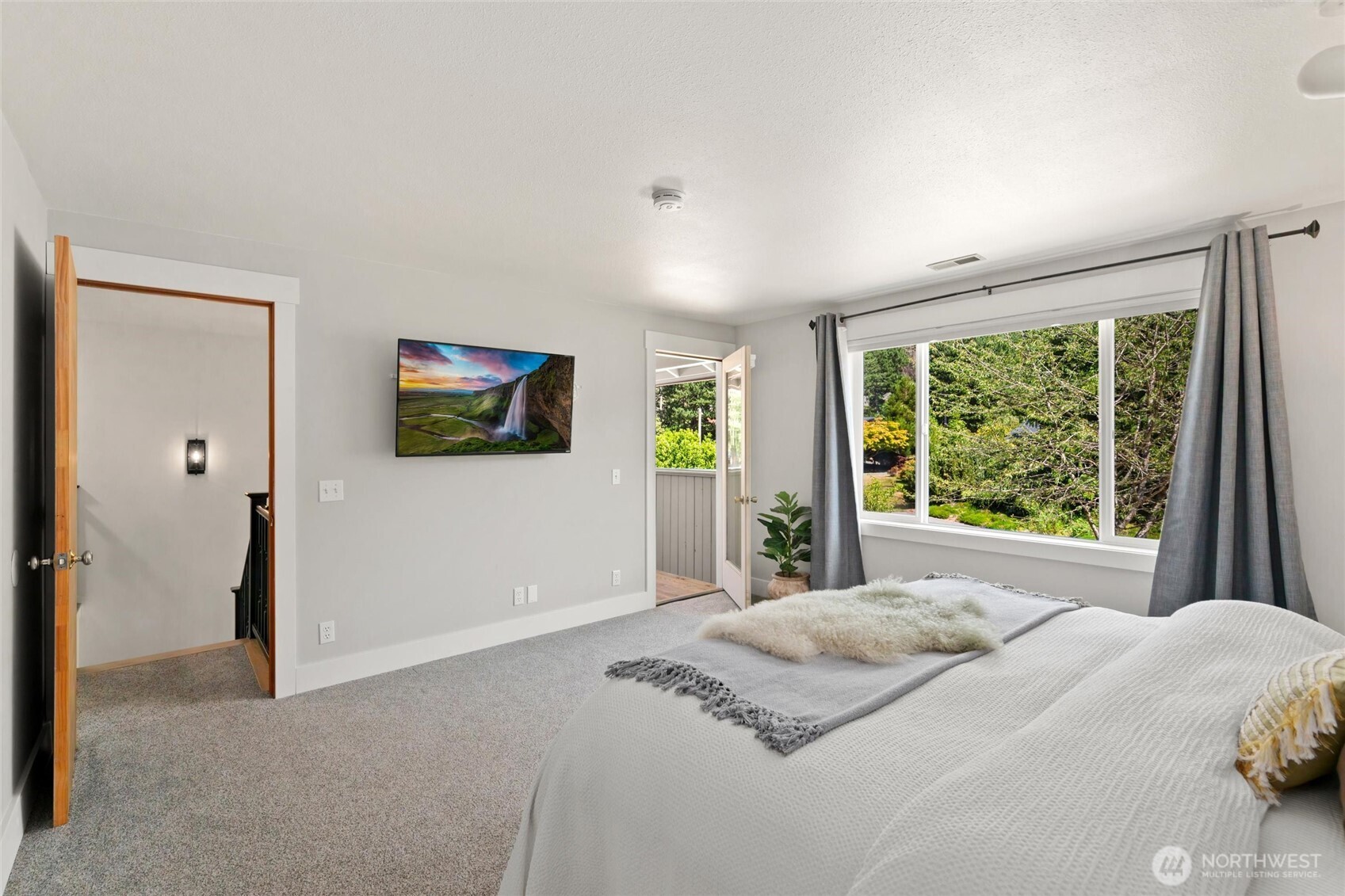 706 Fieldston Road Bellingham, WA 98225 - Photo 23 of 40 a bedroom with a large bed and a flat tv screen next to a window