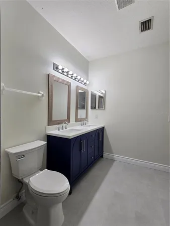 a bathroom with a toilet sink vanity granite and mirror