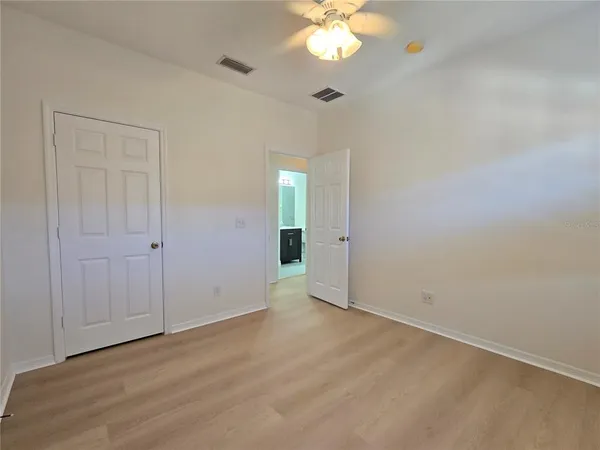 an empty room with wooden floor and chandelier fan