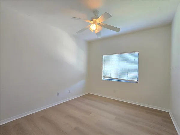 an empty room with a window and chandelier fan