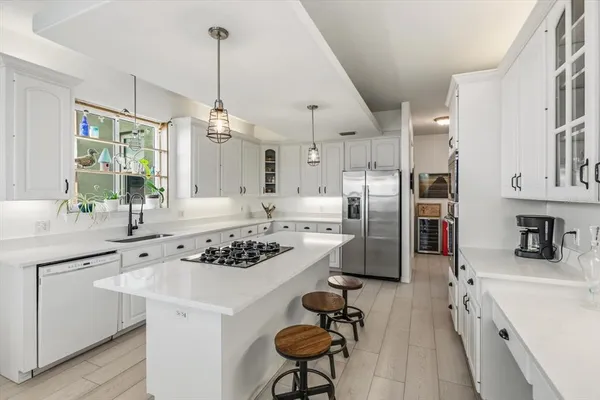 a kitchen with stainless steel appliances a stove a sink a center island and cabinets