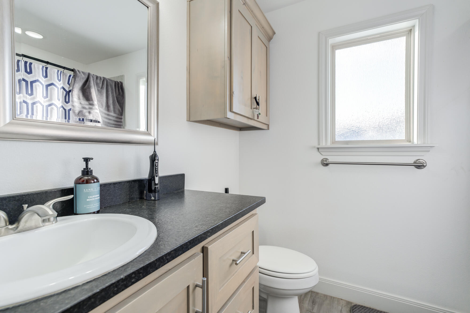 7020 24th Street Lubbock, TX 79407 - Photo 26 of 31 a bathroom with a granite countertop sink a toilet and a mirror