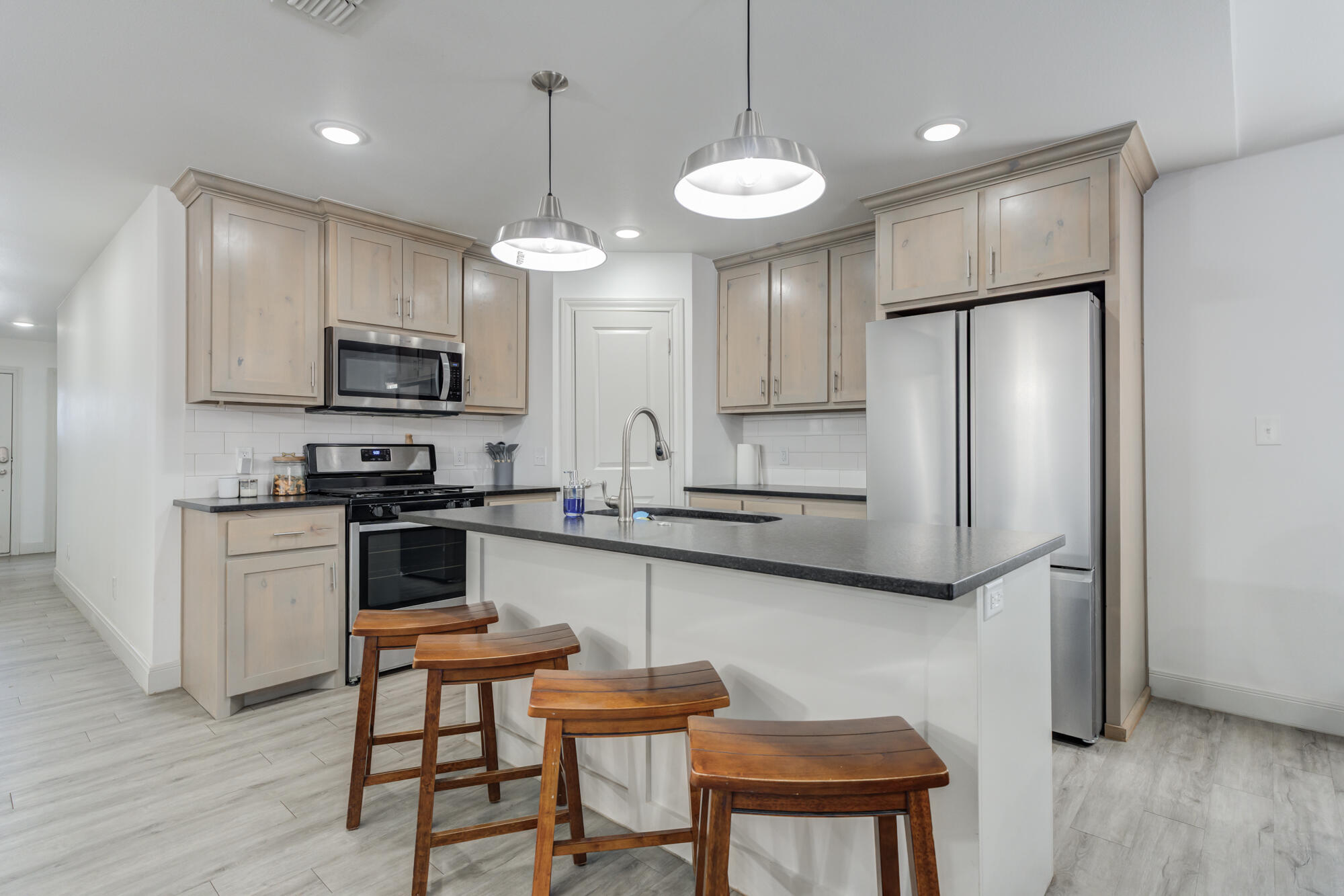 7020 24th Street Lubbock, TX 79407 - Photo 3 of 31 a kitchen with stainless steel appliances kitchen island granite countertop a refrigerator a stove a microwave oven a sink dishwasher and a dining table with wooden floor