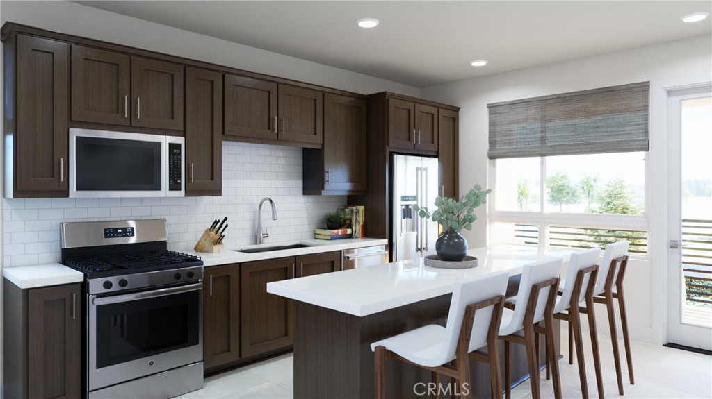 76 Bigsby Drive Stanton, CA 90680 - Photo 5 of 13 a kitchen with a stove a sink a microwave a dining table and chairs