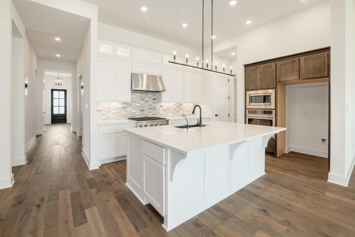 1604 Lilly Grace Bend Leander, TX 78641 - Photo 6 of 22 a kitchen with kitchen island a white counter top space a sink and appliances