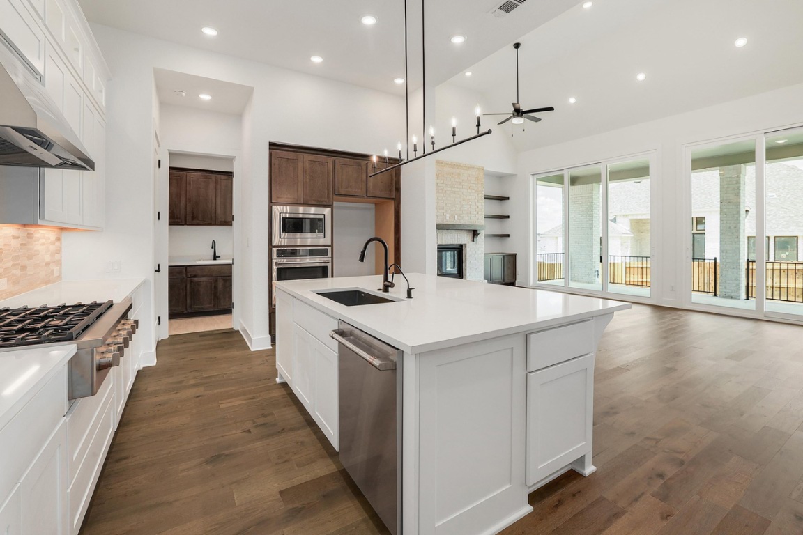 1604 Lilly Grace Bend Leander, TX 78641 - Photo 22 of 22 a kitchen with stainless steel appliances kitchen island a large counter top a stove a sink and a refrigerator