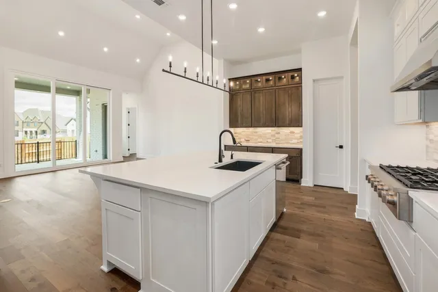 a kitchen with stainless steel appliances kitchen island a large counter top a stove a sink and a refrigerator