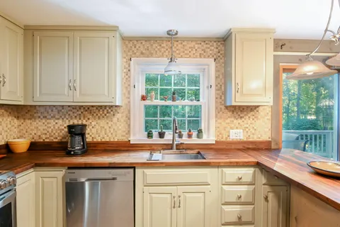 a kitchen with stainless steel appliances granite countertop a sink a window and cabinets