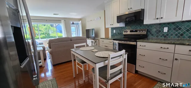 a kitchen with stainless steel appliances granite countertop a stove a refrigerator a sink a stove and white cabinets with wooden floor