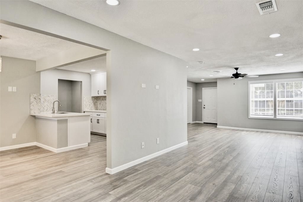 7906 Hammerly Boulevard Houston, TX 77055 - Photo 5 of 22 a view of a kitchen and an empty room with wooden floor and a window