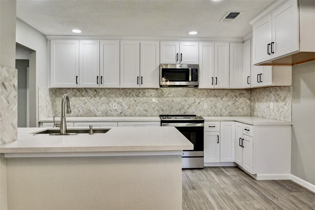 7906 Hammerly Boulevard Houston, TX 77055 - Photo 9 of 22 a kitchen with stainless steel appliances granite countertop a sink a stove a microwave and cabinets