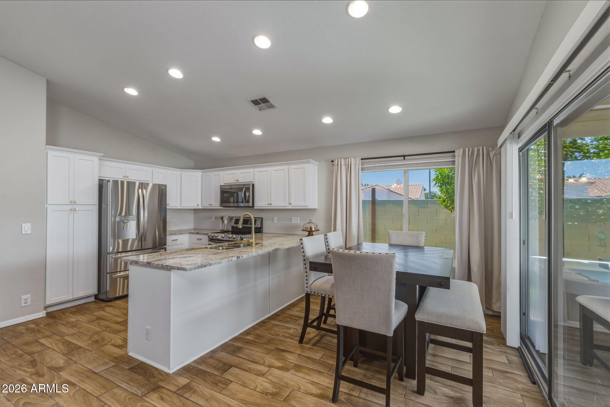 9242 West St John Road Peoria, AZ 85382 - Photo 31 of 59 a kitchen with kitchen island a table and chairs