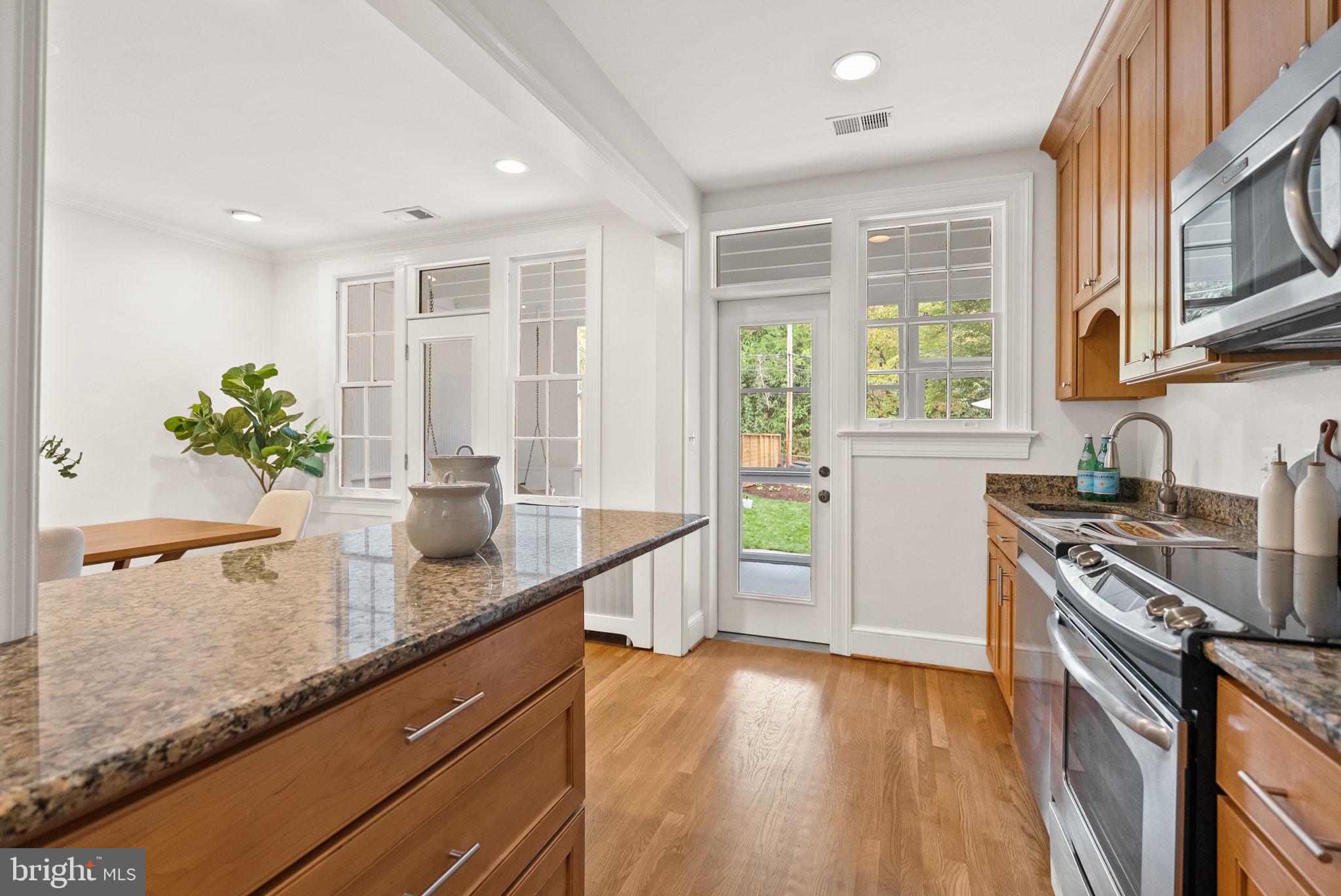 3819 T Street Northwest Washington, DC 20007 - Photo 7 of 27 a kitchen with stainless steel appliances granite countertop a sink a stove a refrigerator wooden floor and a large window