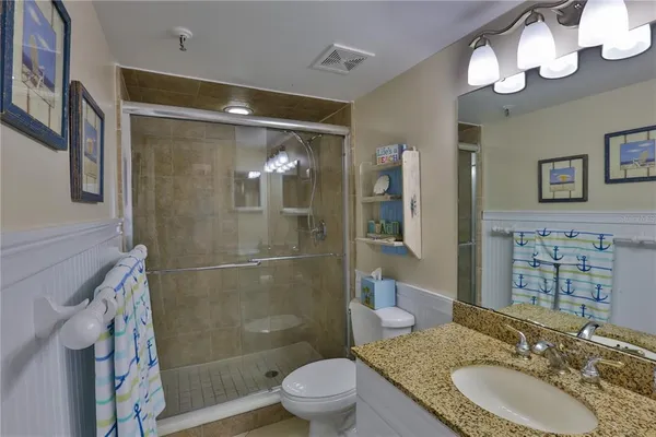a bathroom with a granite countertop sink toilet and shower