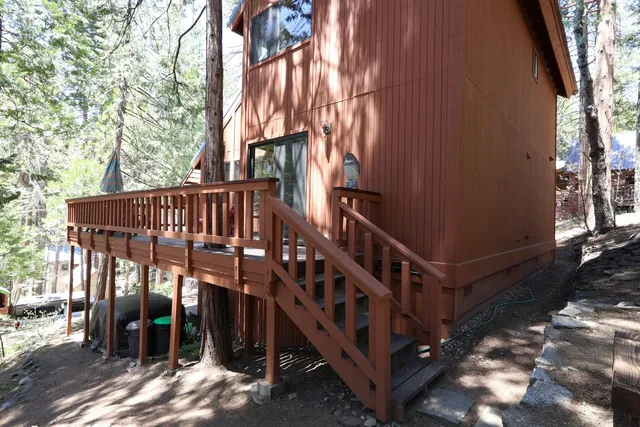 a view of wooden house with a large trees