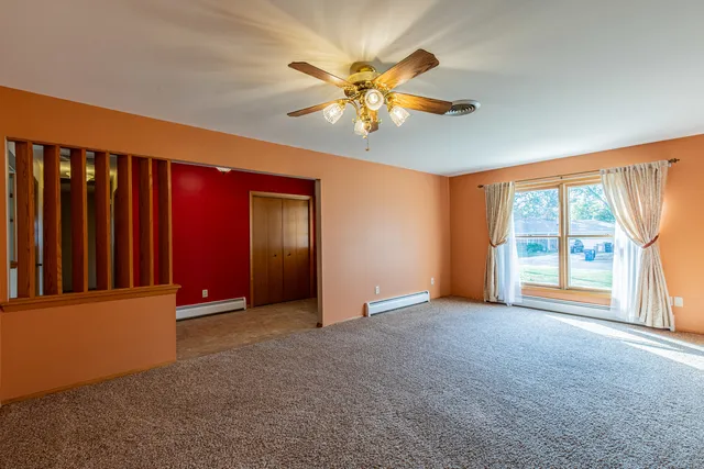a view of an empty room with window and a ceiling fan