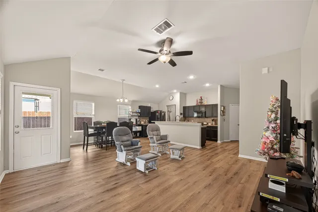 a living room with furniture kitchen view and a wooden floor