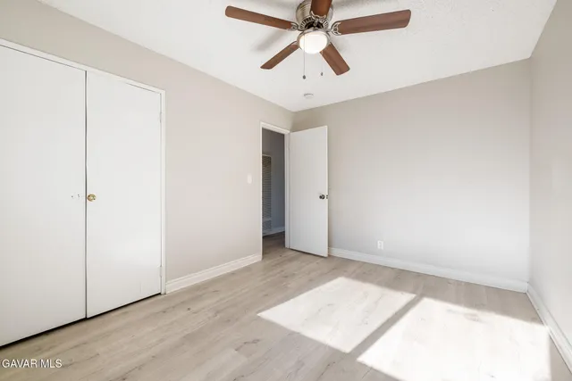 an empty room with a window and a fan