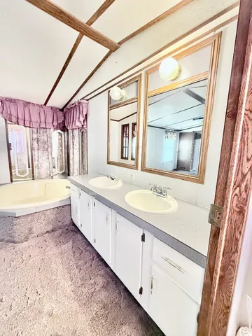 a bathroom with a granite countertop tub sink and mirror
