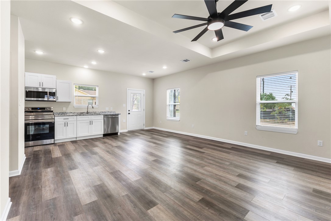 1601 West 17th Street Bryan, TX 77803 - Photo 3 of 16 an empty room with wooden floor kitchen view and windows