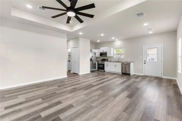a view of a kitchen with a stove cabinets a ceiling fan and wooden floor