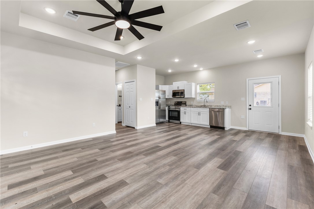 1601 West 17th Street Bryan, TX 77803 - Photo 4 of 16 a view of a kitchen with a stove cabinets a ceiling fan and wooden floor