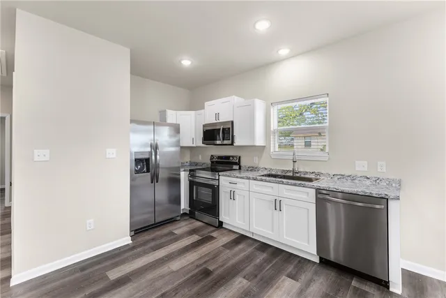 a kitchen with stainless steel appliances granite countertop a stove top oven a sink and dishwasher a refrigerator with wooden floor