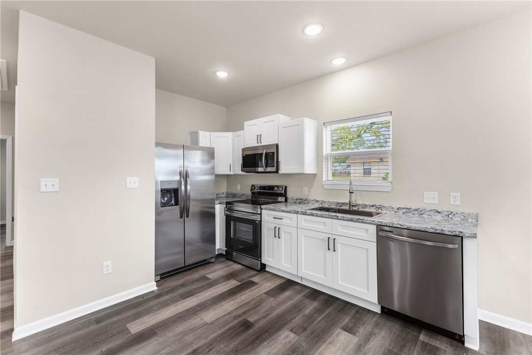 1601 West 17th Street Bryan, TX 77803 - Photo 6 of 16 a kitchen with stainless steel appliances granite countertop a stove top oven a sink and dishwasher a refrigerator with wooden floor