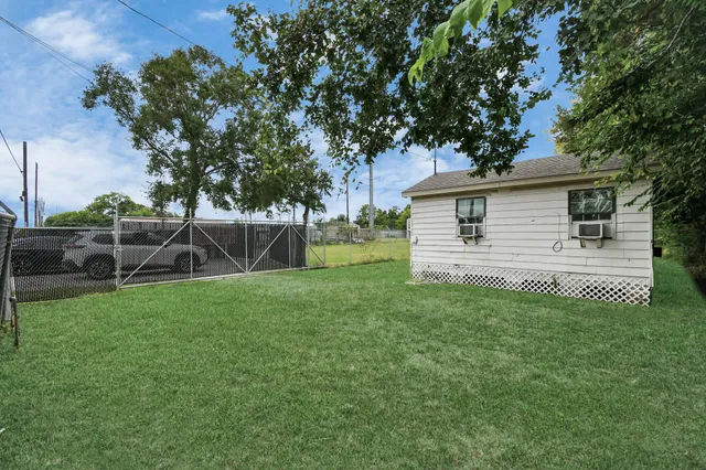 a backyard of a house with plants and large tree