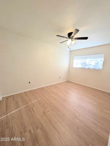 an empty room with a window and a ceiling fan