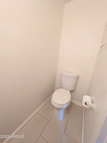 a white toilet sitting next to a white wall