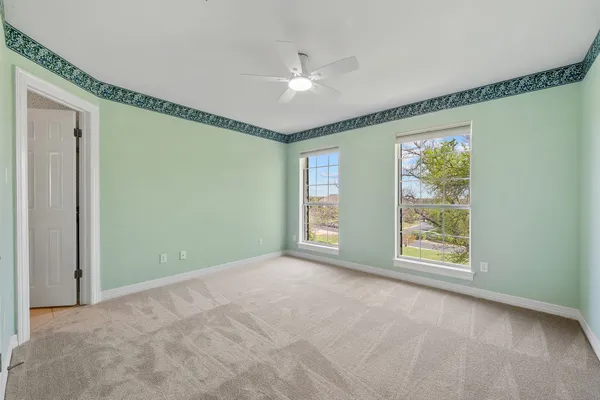 a view of an empty room with windows and chandelier fan