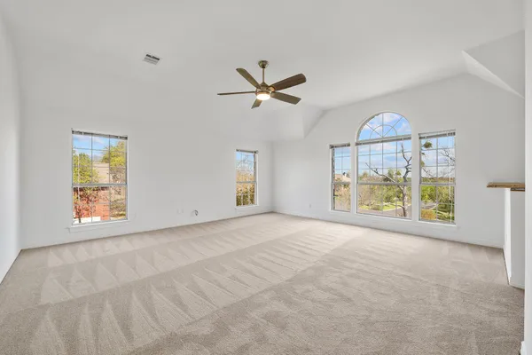 an empty room with windows and fan