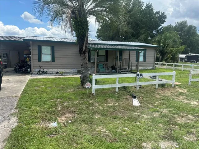 a view of a house with a yard fire pit and a large tree