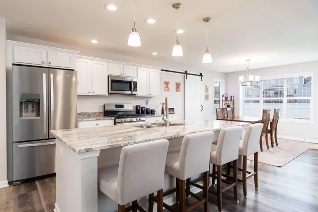 a kitchen with stainless steel appliances granite countertop a refrigerator a stove a microwave oven a dining table and chairs