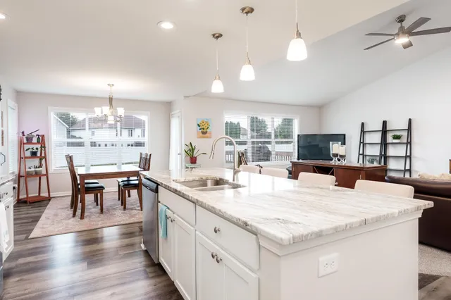 a large kitchen with kitchen island a stove a dining table and chairs with wooden floor