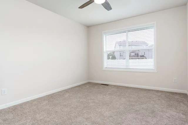 an empty room with a window and a ceiling fan