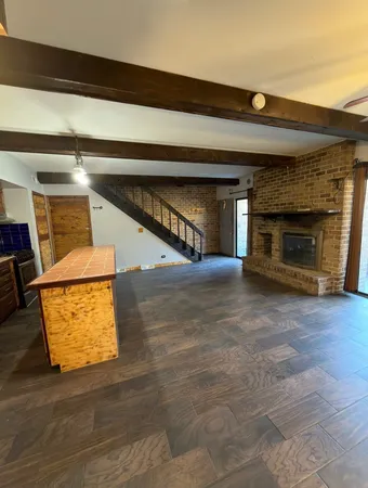 a view of an empty room with wooden floor and a fireplace