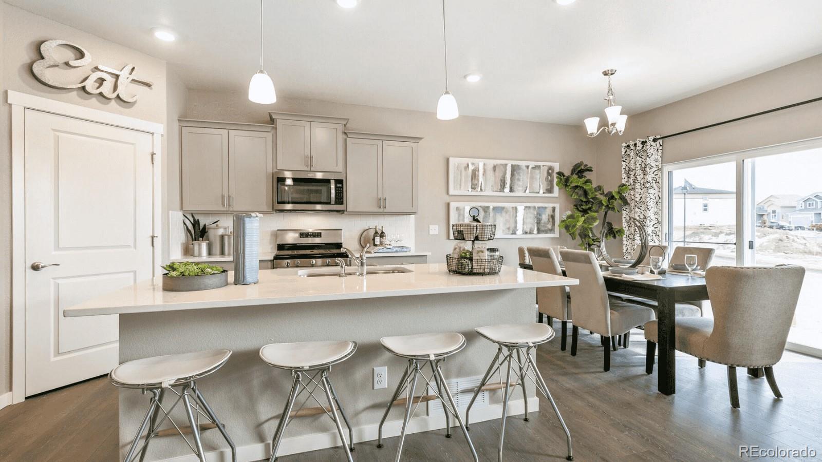 810 North Clubview Street Watkins, CO 80137 - Photo 5 of 21 a kitchen with stainless steel appliances granite countertop a stove top oven a refrigerator a dining table and chairs with wooden floor