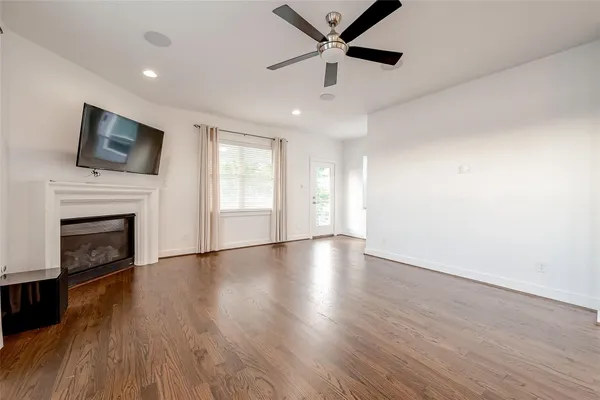 a view of an empty room with wooden floor and a fireplace