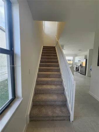 a view of staircase with lots of frames on wall and a large window