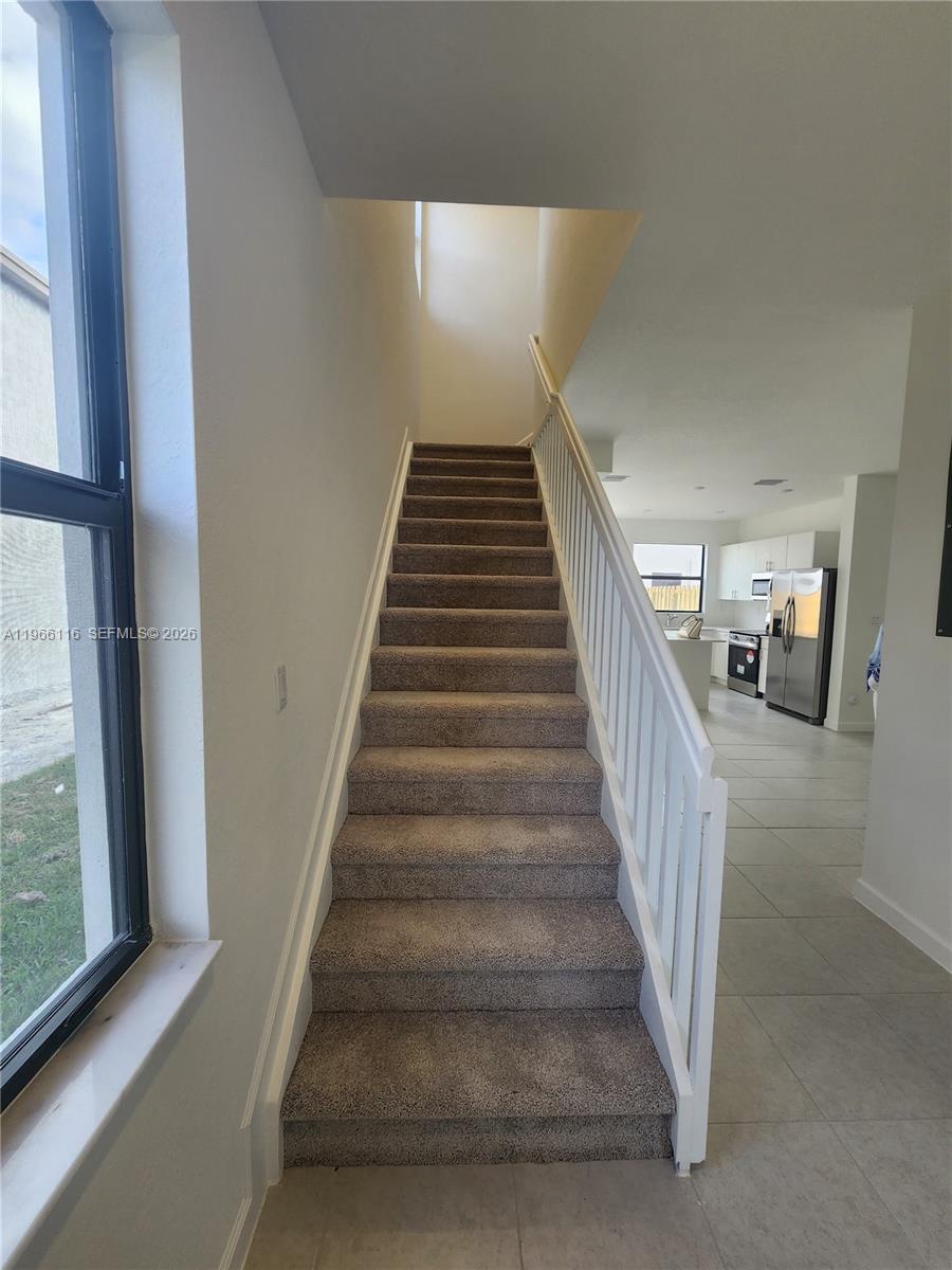 23331 Southwest 128th Avenue, Unit 23331 Homestead, FL 33032 - Photo 2 of 16 a view of staircase with lots of frames on wall and a large window