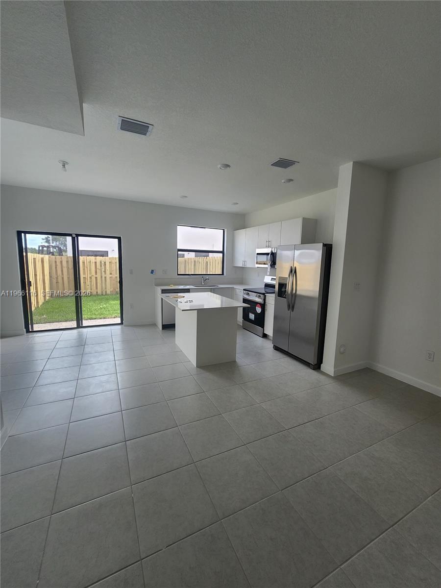 23331 Southwest 128th Avenue, Unit 23331 Homestead, FL 33032 - Photo 4 of 16 a living room with couches and kitchen view